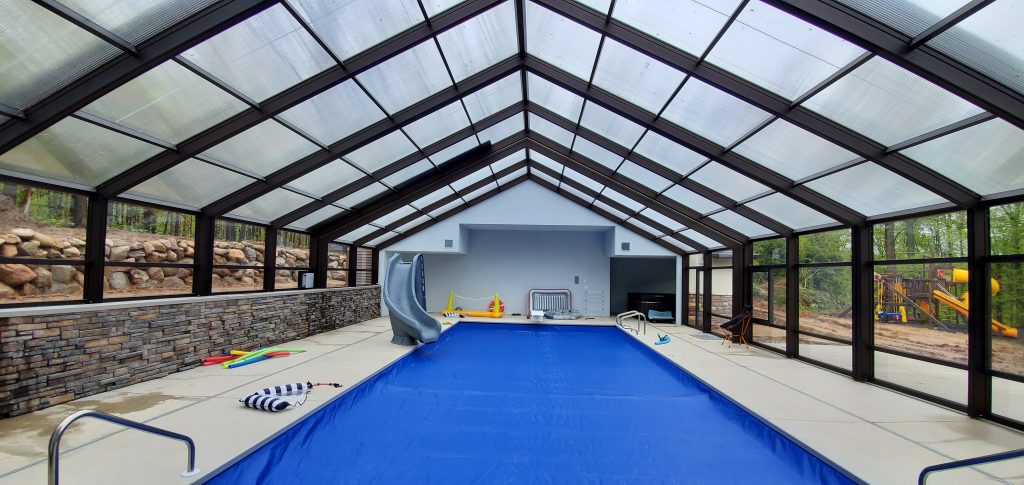 DynaDome | An indoor pool with a retractable enclosure and glass walls.