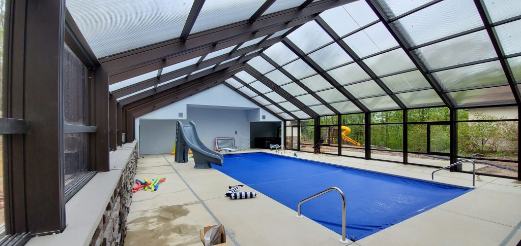 DynaDome | An indoor pool with a retractable enclosure and glass walls.