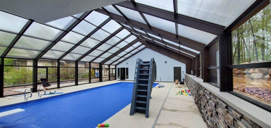 DynaDome | An indoor pool with a retractable enclosure and glass walls.