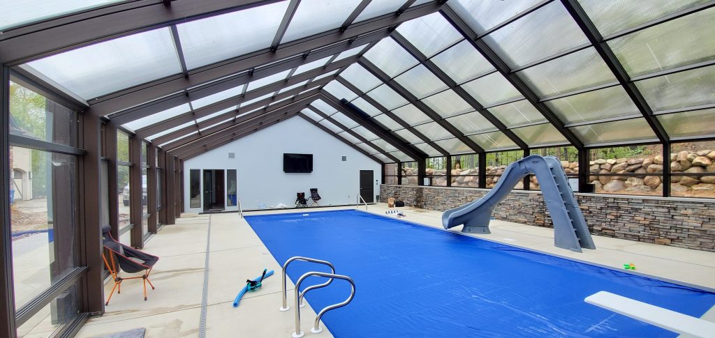 DynaDome | An indoor pool with a retractable enclosure and glass walls.