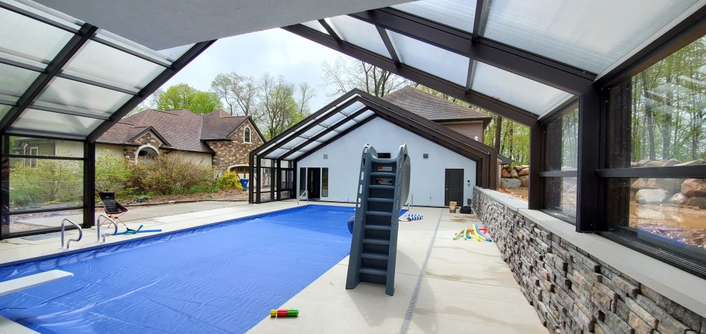 DynaDome | A house with a retractable enclosure containing a swimming pool and a slide.