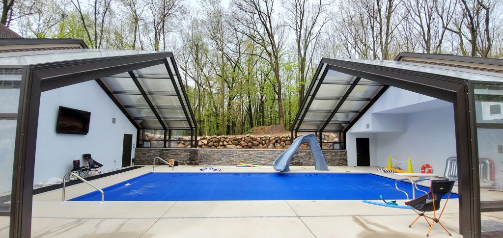 DynaDome | A swimming pool in a backyard with a retractable enclosure.