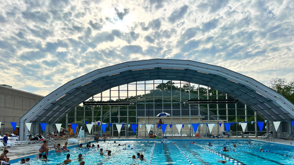 DynaDome | People swimming in a pool under a retractable enclosure.