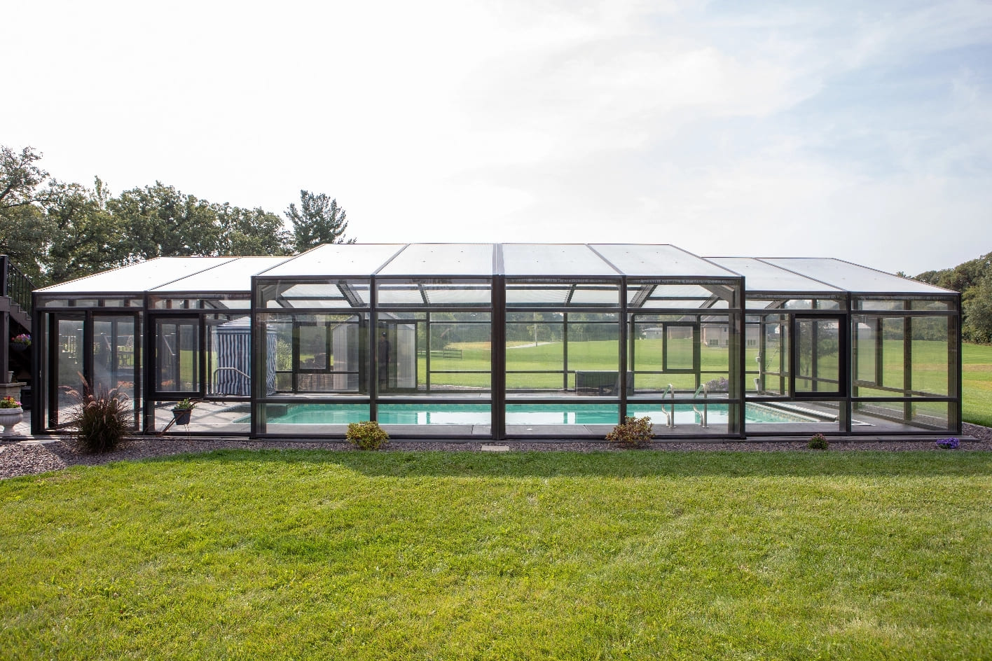 DynaDome | A glass enclosed swimming pool in a backyard, perfect for a tranquil home oasis.