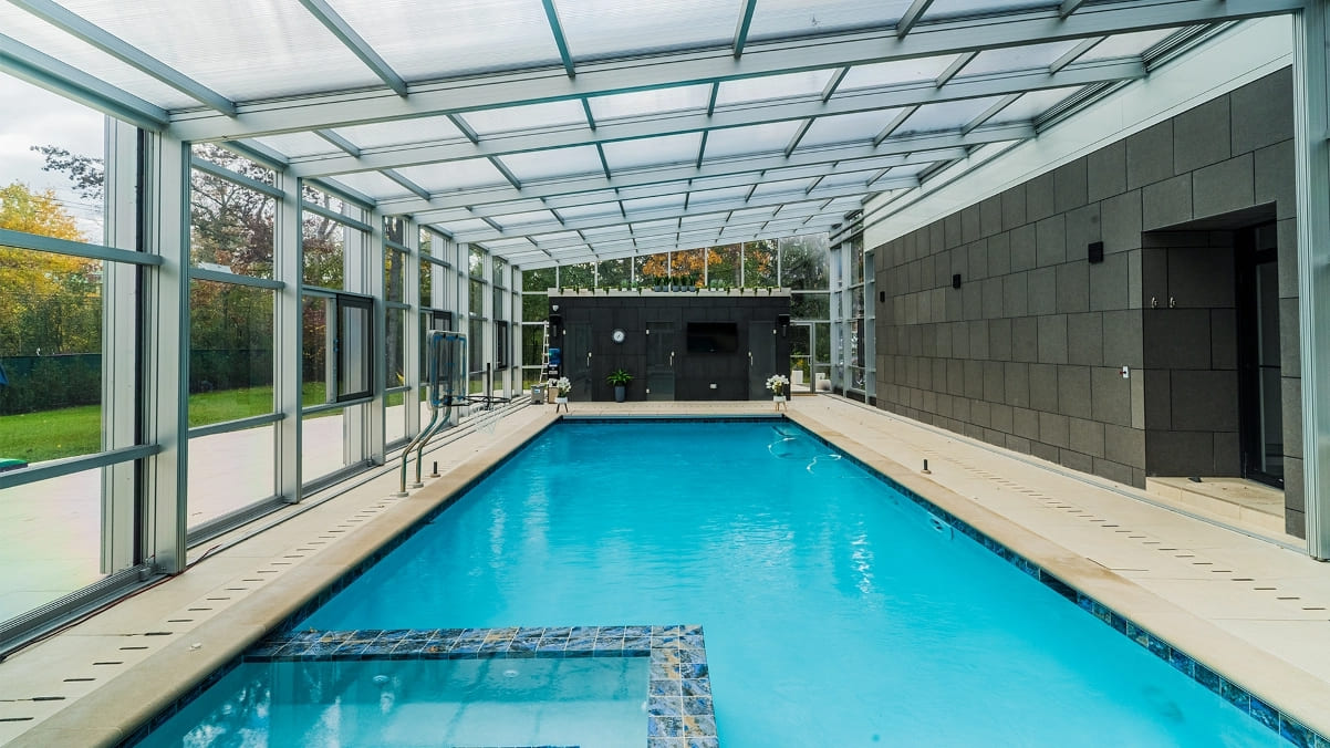 DynaDome |         A glass-walled swimming pool in a home.
